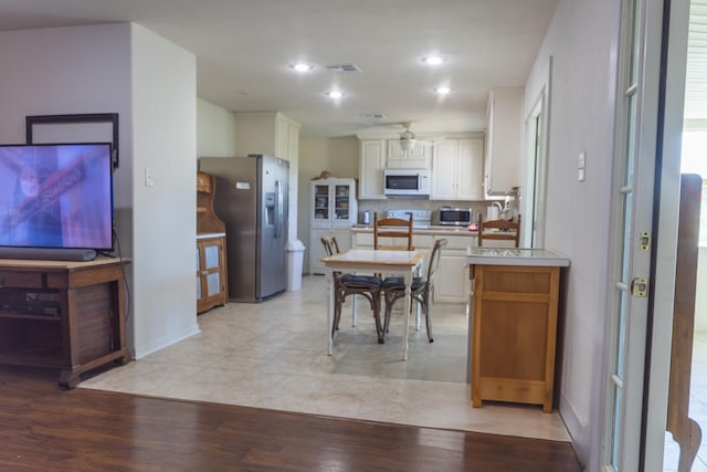6470 Wilder Dr, Beaumont, TX 77706 - kitchen featuring stainless steel appliances, ceiling fan, light wood-type flooring, white cabinetry, and tasteful backsplash