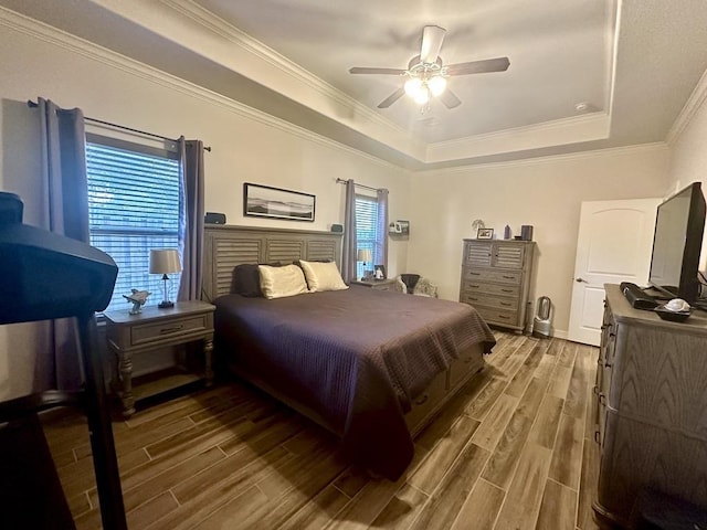 bedroom with wood-type flooring, a tray ceiling, ceiling fan, and ornamental molding