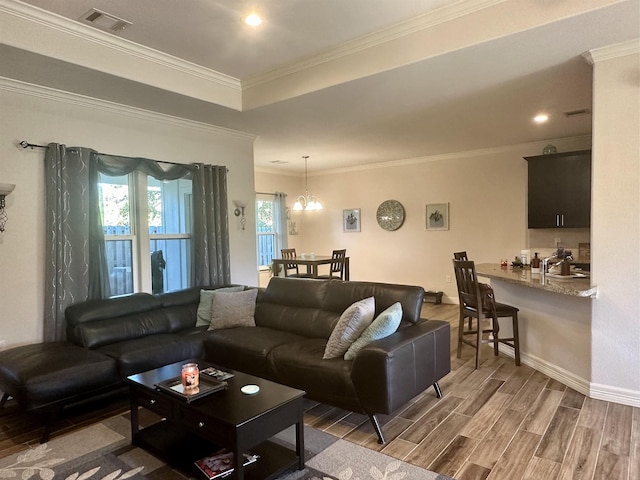 living room featuring hardwood / wood-style floors, a notable chandelier, ornamental molding, and sink