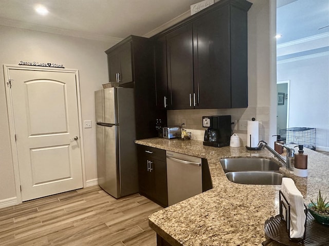 kitchen with sink, ornamental molding, light wood-type flooring, and appliances with stainless steel finishes