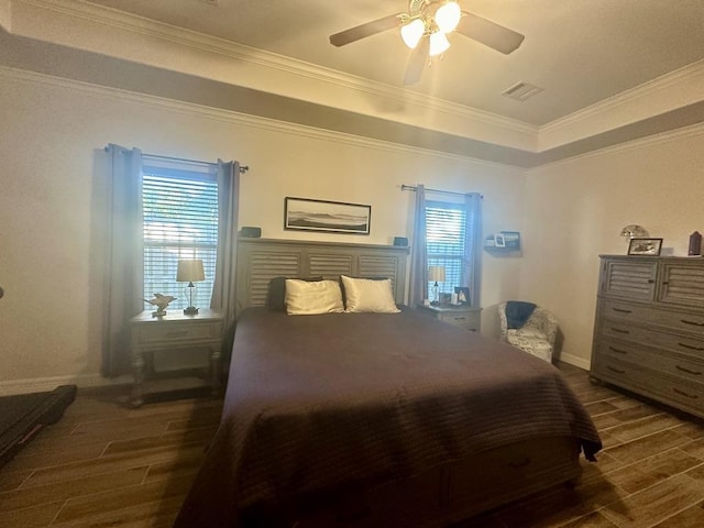 bedroom with ceiling fan, dark hardwood / wood-style flooring, crown molding, and a tray ceiling