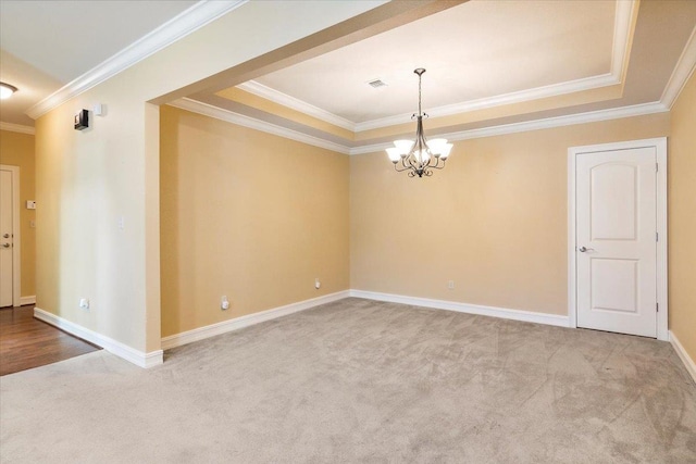 empty room with a tray ceiling, ornamental molding, light colored carpet, and a notable chandelier