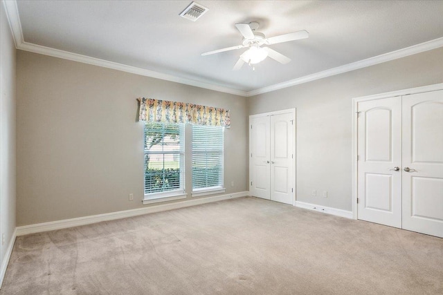 unfurnished bedroom with two closets, light colored carpet, ceiling fan, and crown molding