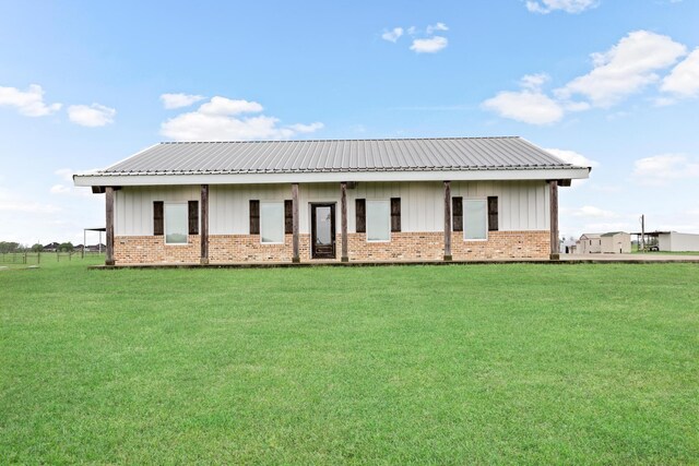 2050 Aggie Dr, Beaumont, TX 77713 - rear view of house with board and batten siding, brick siding, metal roof, and a lawn