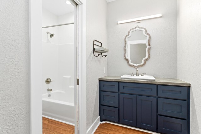 2050 Aggie Dr, Beaumont, TX 77713 - full bath featuring a textured wall, wood finished floors, vanity, and washtub / shower combination