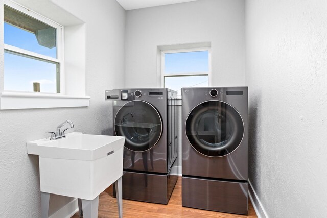 2050 Aggie Dr, Beaumont, TX 77713 - clothes washing area with laundry area, a sink, light wood-style floors, a textured wall, and separate washer and dryer