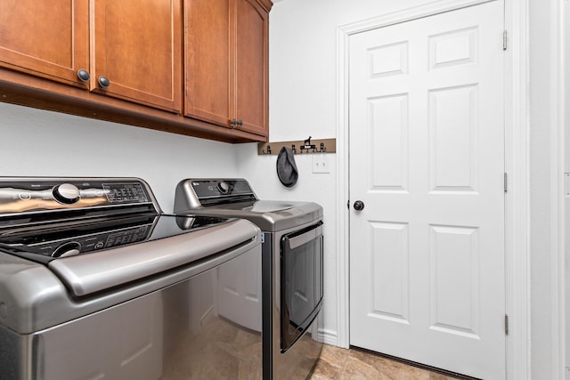 clothes washing area featuring washer and clothes dryer and cabinets