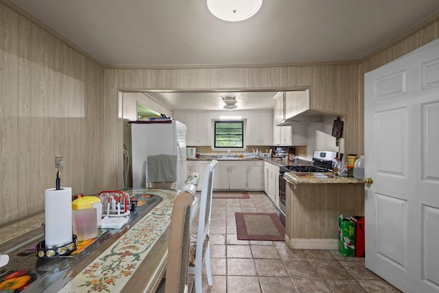 2850 S Major Dr, Beaumont, TX 77707 - kitchen with stainless steel gas stove, ornamental molding, white cabinets, freestanding refrigerator, and light countertops