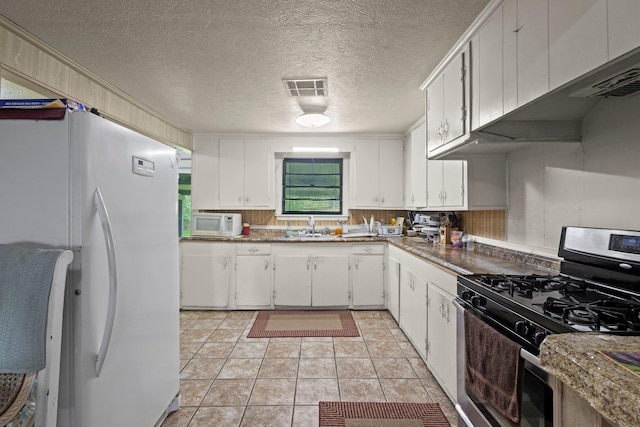 2850 S Major Dr, Beaumont, TX 77707 - kitchen featuring white appliances, white cabinets, light tile patterned floors, and a textured ceiling