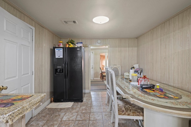 2850 S Major Dr, Beaumont, TX 77707 - kitchen featuring black fridge, ornamental molding, light tile patterned flooring, and wood walls
