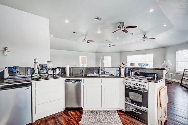 kitchen with gas range, white cabinetry, sink, and fridge