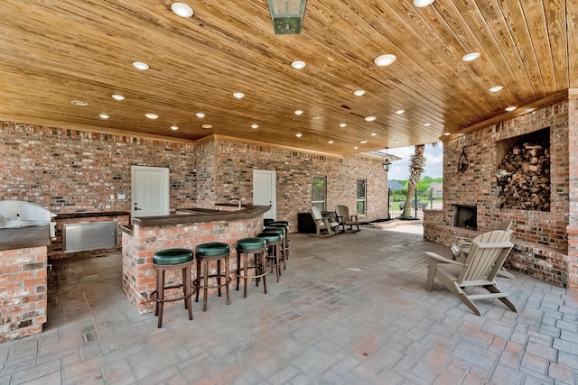 view of patio / terrace featuring an outdoor kitchen, an outdoor brick fireplace, an outdoor bar, and a grill