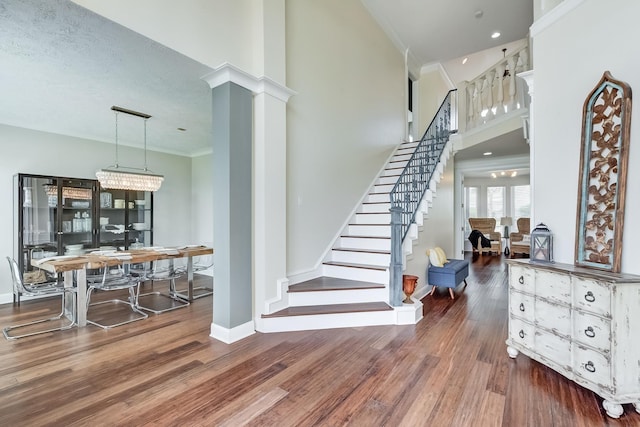 stairs with a chandelier, hardwood / wood-style floors, a textured ceiling, and crown molding