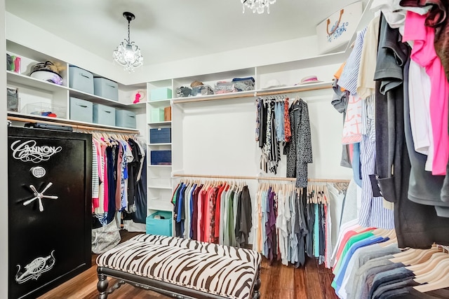 walk in closet with dark hardwood / wood-style floors and an inviting chandelier