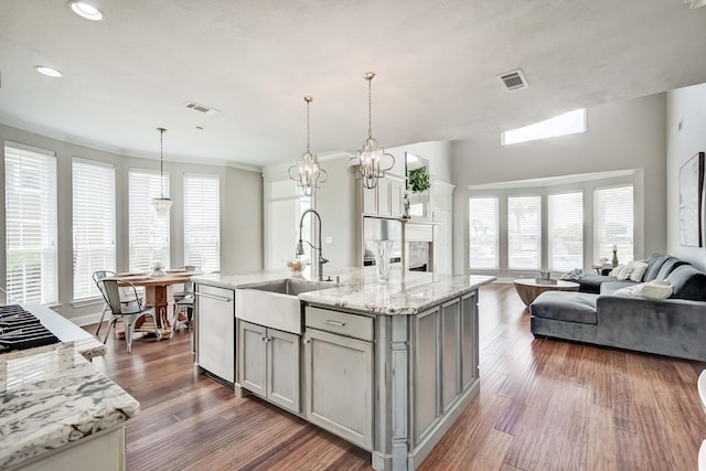 kitchen featuring a center island with sink, gray cabinets, sink, and hanging light fixtures