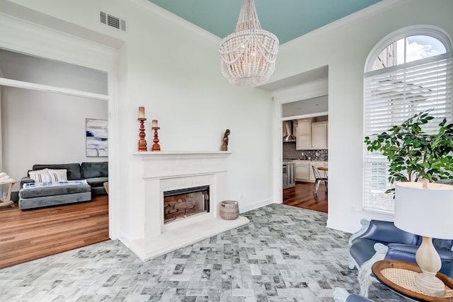 living room featuring light hardwood / wood-style flooring, an inviting chandelier, and crown molding