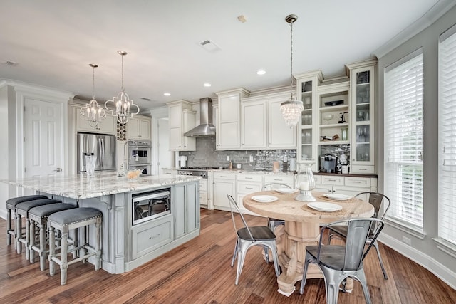 kitchen featuring decorative light fixtures, wall chimney exhaust hood, tasteful backsplash, a large island, and stainless steel appliances