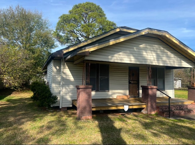 bungalow-style house featuring covered porch and a front lawn