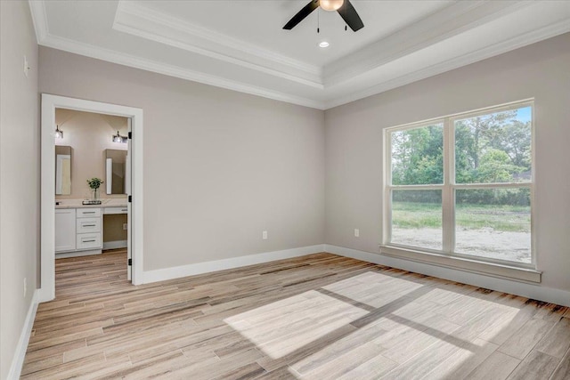 unfurnished bedroom featuring ensuite bathroom, a raised ceiling, crown molding, light hardwood / wood-style flooring, and ceiling fan