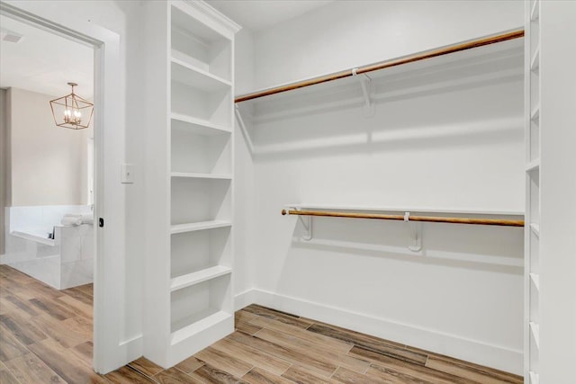 walk in closet featuring light hardwood / wood-style floors and a chandelier