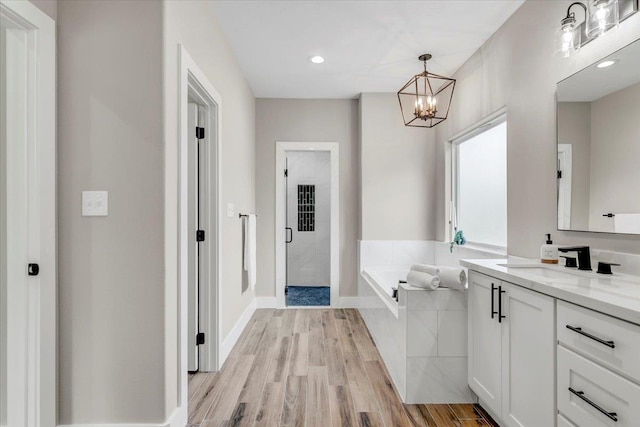 bathroom featuring hardwood / wood-style flooring, vanity, shower with separate bathtub, and an inviting chandelier