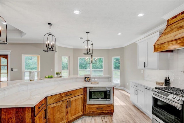 kitchen featuring crown molding, white cabinets, stainless steel appliances, and light wood-type flooring