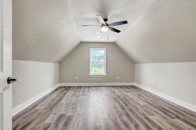 additional living space with hardwood / wood-style floors, ceiling fan, a textured ceiling, and vaulted ceiling