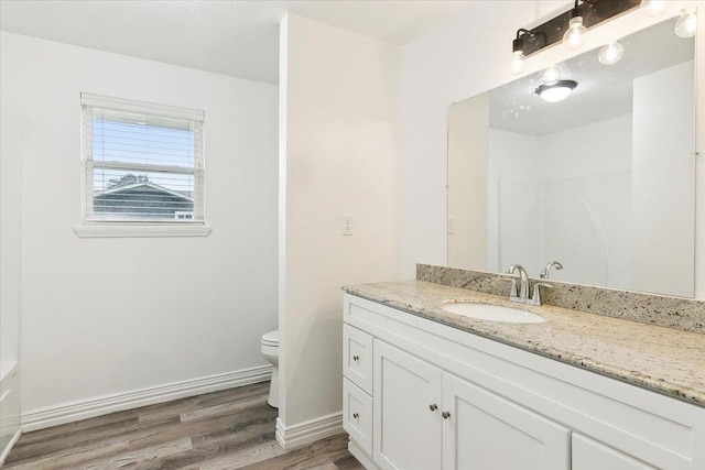 bathroom featuring wood-type flooring, vanity, and toilet