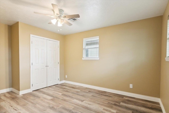 unfurnished bedroom featuring a textured ceiling, ceiling fan, light hardwood / wood-style flooring, and a closet