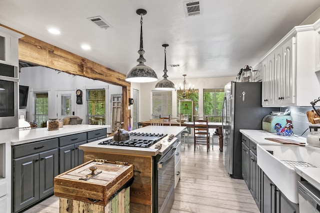 kitchen featuring a kitchen island, white cabinetry, gray cabinetry, hanging light fixtures, and stainless steel appliances