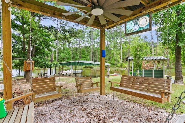 view of yard with a water view, ceiling fan, and a dock