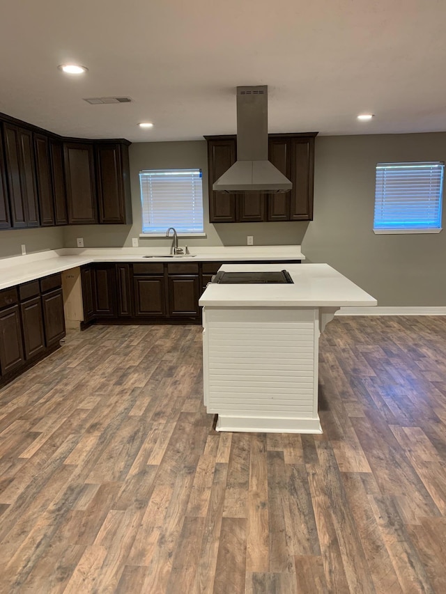 kitchen with visible vents, a sink, wood finished floors, stovetop, and island range hood