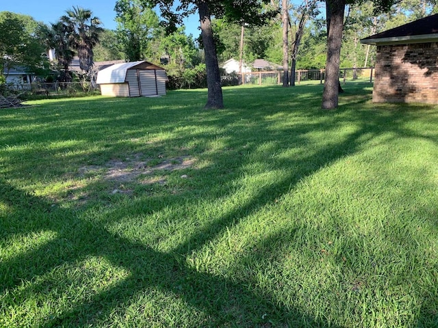 view of yard featuring an outbuilding, a storage unit, and fence