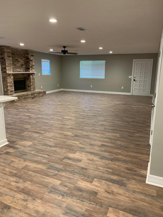 unfurnished living room featuring recessed lighting, baseboards, dark wood-style floors, and a fireplace