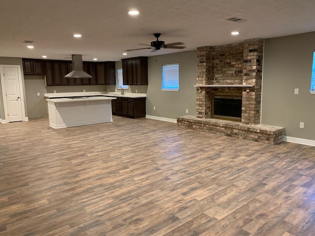 kitchen featuring visible vents, ventilation hood, open floor plan, a fireplace, and a sink