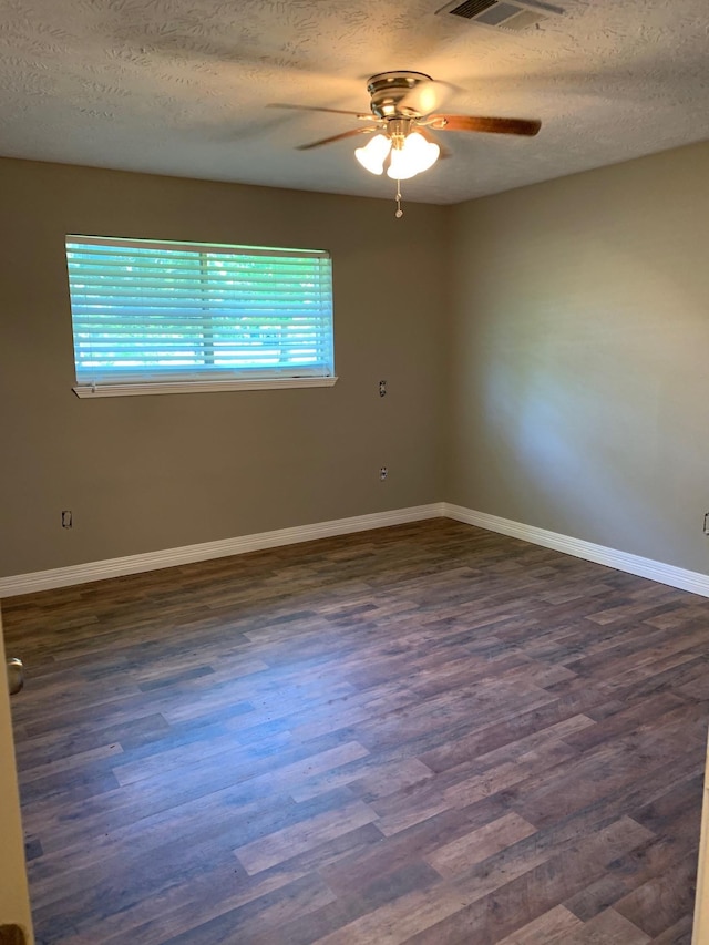 empty room featuring visible vents, a textured ceiling, baseboards, ceiling fan, and dark wood-style flooring