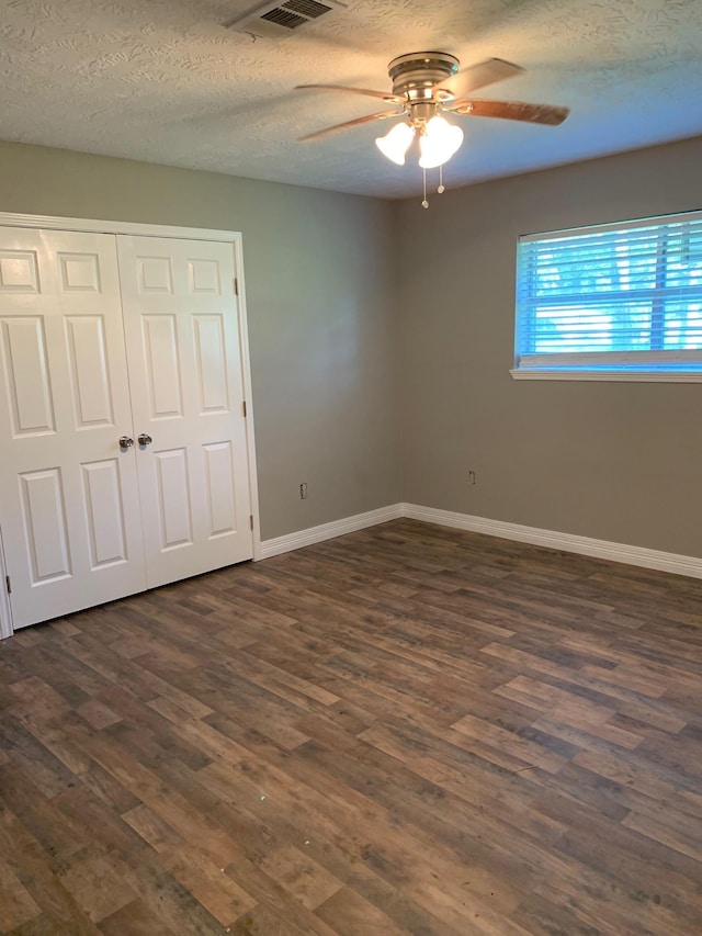 unfurnished bedroom featuring visible vents, baseboards, dark wood finished floors, a closet, and a textured ceiling