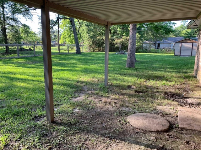 view of yard with a storage shed, an outbuilding, and fence