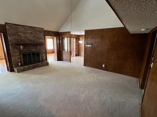 unfurnished living room featuring a fireplace, light colored carpet, high vaulted ceiling, and wooden walls