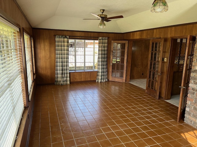 empty room with ceiling fan, wooden walls, and lofted ceiling