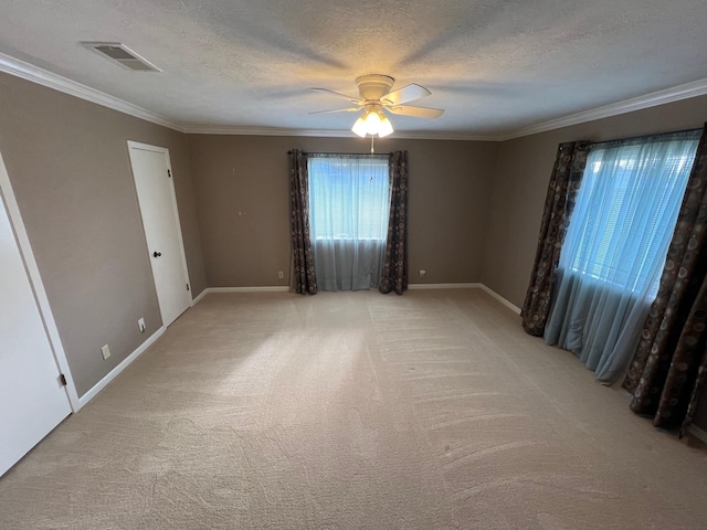 empty room featuring light carpet, crown molding, ceiling fan, and a textured ceiling