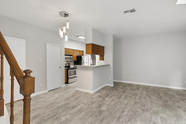 kitchen featuring kitchen peninsula, light stone counters, light hardwood / wood-style flooring, and stainless steel appliances