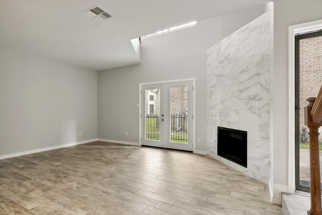 unfurnished living room with a tile fireplace and french doors