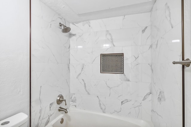 bathroom featuring toilet and tiled shower / bath