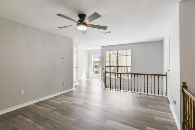 unfurnished room with ceiling fan, dark wood-type flooring, and a textured ceiling