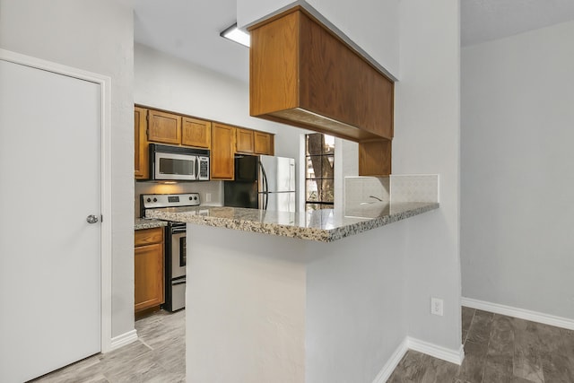 kitchen featuring light stone countertops, appliances with stainless steel finishes, and kitchen peninsula