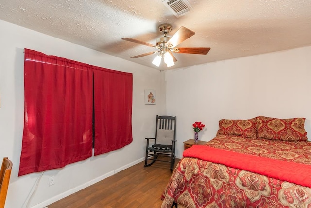 bedroom featuring visible vents, ceiling fan, a textured ceiling, wood finished floors, and baseboards