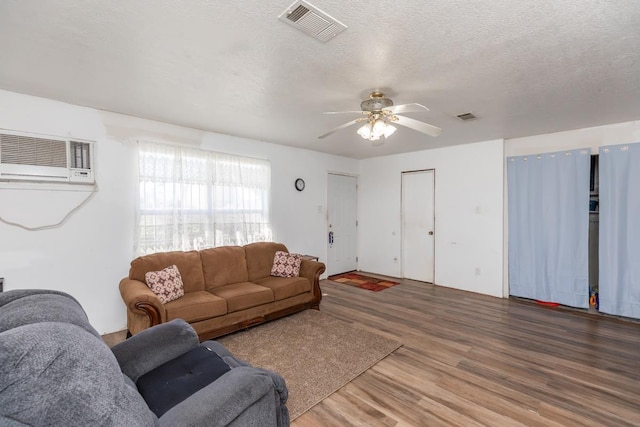 living room featuring a textured ceiling, ceiling fan, wood finished floors, and visible vents