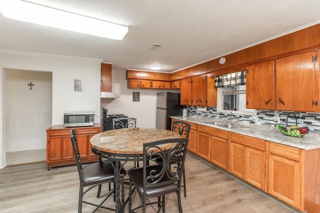 kitchen with stainless steel appliances, light countertops, visible vents, backsplash, and a sink