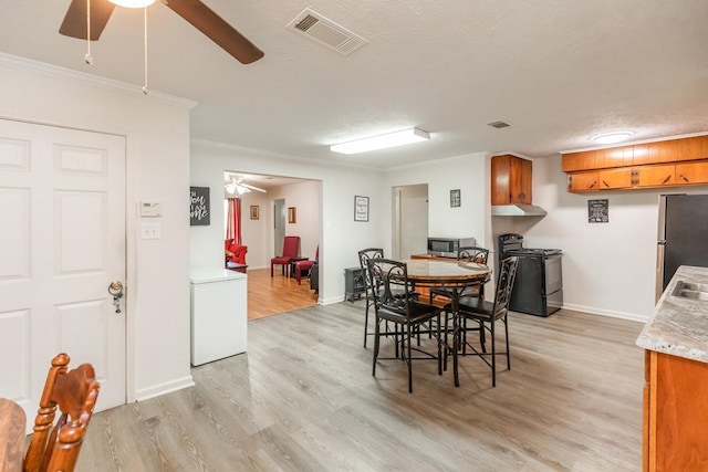 dining space with light wood-type flooring, ceiling fan, visible vents, and crown molding